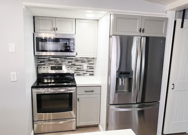 kitchen featuring light countertops, tasteful backsplash, gray cabinets, and stainless steel appliances