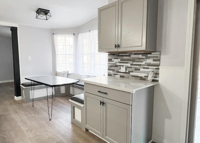 kitchen with light wood-type flooring, backsplash, gray cabinets, and light countertops