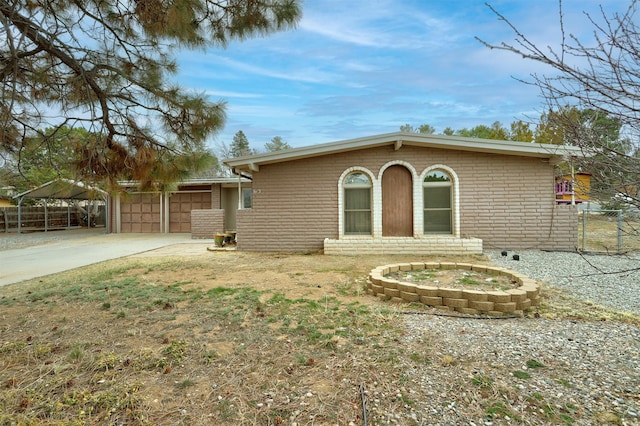 view of front of property featuring brick siding, concrete driveway, an attached garage, and fence