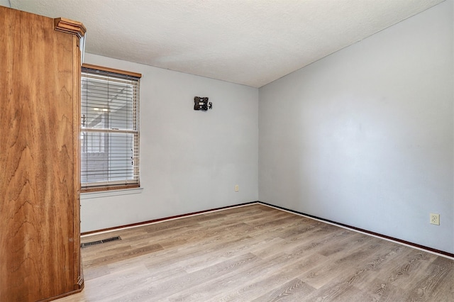 unfurnished room with visible vents, a textured ceiling, and wood finished floors