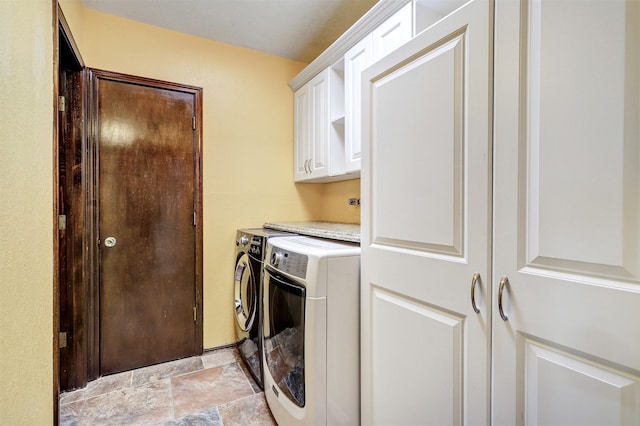 laundry room with cabinet space, stone finish floor, and washer and clothes dryer