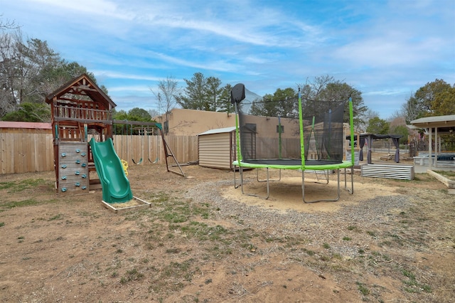 view of play area with a storage shed, a trampoline, fence, and an outdoor structure