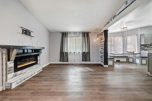 living area with a glass covered fireplace, baseboards, and wood finished floors