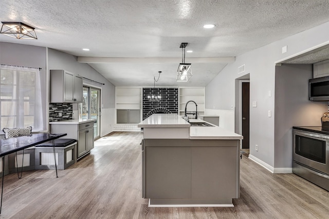 kitchen featuring lofted ceiling with beams, gray cabinets, a sink, light countertops, and appliances with stainless steel finishes