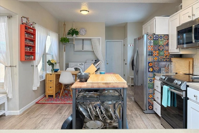 kitchen featuring washer and clothes dryer, light wood-style floors, baseboards, and stainless steel appliances