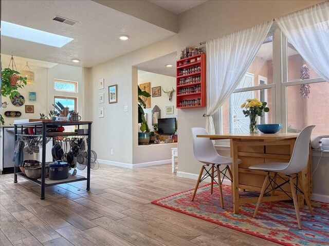 dining space with wood finished floors, visible vents, baseboards, a skylight, and recessed lighting