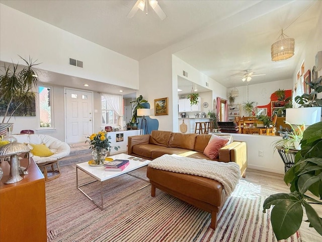 living room with visible vents, wood finished floors, and ceiling fan