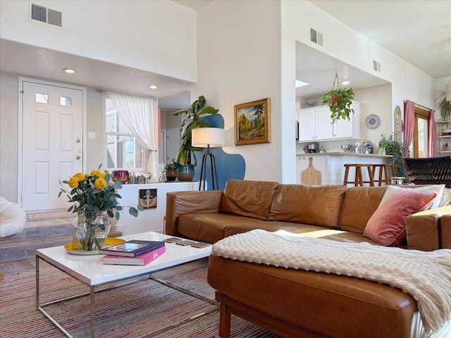 living area with a high ceiling, recessed lighting, and visible vents