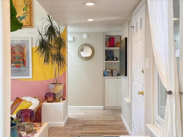 hall featuring recessed lighting, baseboards, and light wood-type flooring