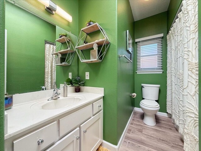 full bath with baseboards, toilet, wood finished floors, and vanity