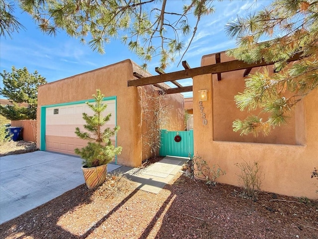 exterior space with stucco siding, a gate, fence, concrete driveway, and a garage