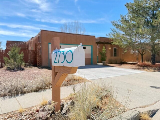 community / neighborhood sign featuring driveway, an attached garage, and fence