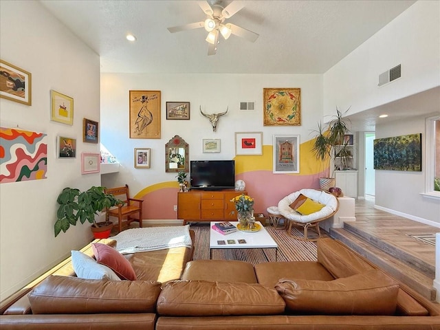 living area featuring visible vents, baseboards, ceiling fan, and wood finished floors