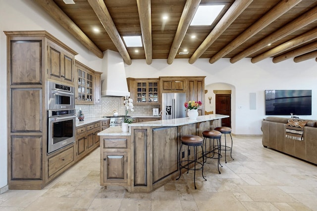 kitchen featuring custom exhaust hood, arched walkways, stainless steel appliances, wood ceiling, and tasteful backsplash