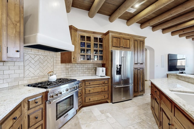 kitchen with brown cabinets, high quality appliances, decorative backsplash, custom exhaust hood, and wood ceiling