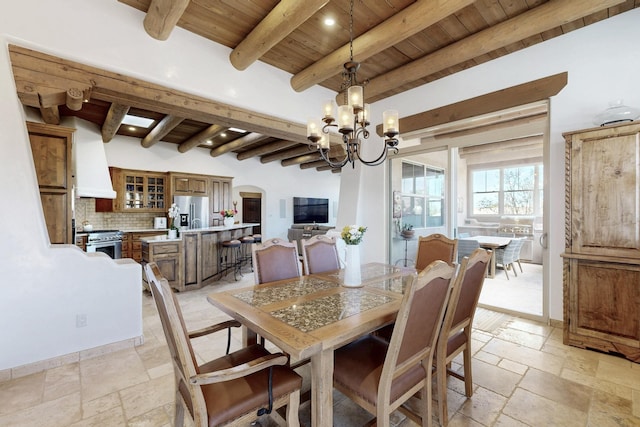 dining space with stone tile floors, beam ceiling, wooden ceiling, and an inviting chandelier