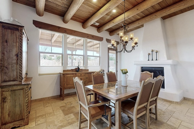 dining area featuring baseboards, a notable chandelier, wood ceiling, and stone tile flooring