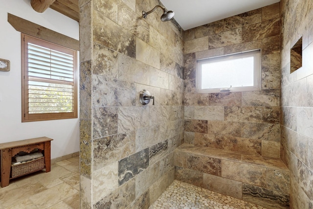 bathroom featuring stone finish flooring and tiled shower