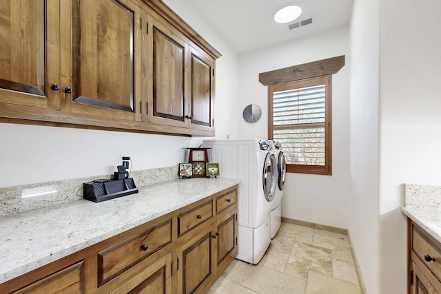 laundry area with visible vents, baseboards, cabinet space, stone tile flooring, and washing machine and dryer