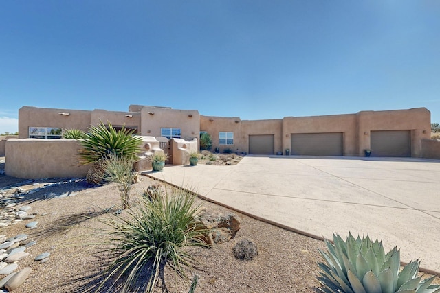 adobe home with concrete driveway, an attached garage, and stucco siding