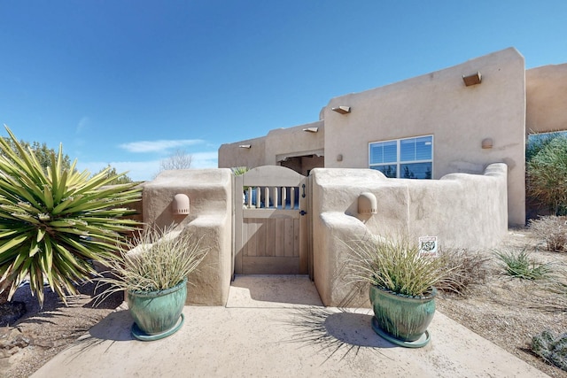 exterior space with a gate and stucco siding