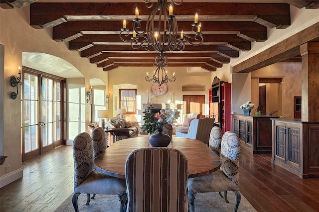 dining area featuring arched walkways, dark wood finished floors, french doors, and an inviting chandelier