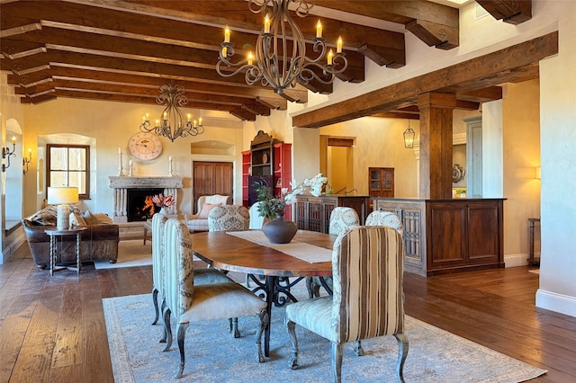 dining room featuring beamed ceiling, a warm lit fireplace, dark wood-style floors, arched walkways, and baseboards