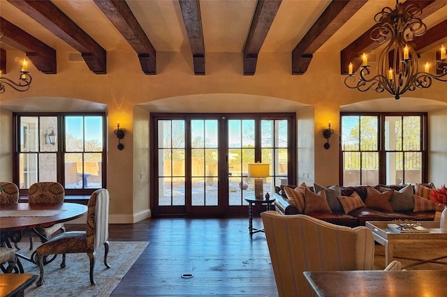 living area with beamed ceiling, a notable chandelier, dark wood-style floors, and baseboards