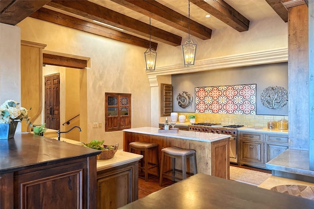 kitchen with a center island, beamed ceiling, a breakfast bar, decorative backsplash, and stainless steel stove