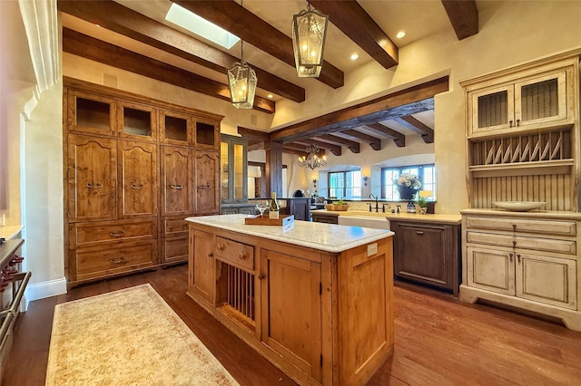 kitchen with glass insert cabinets, a kitchen island, light countertops, and dark wood-style flooring