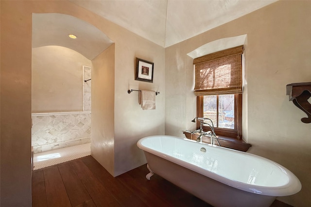 full bath with hardwood / wood-style floors and a soaking tub