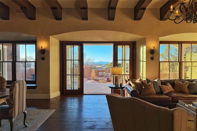 living room featuring a notable chandelier, plenty of natural light, dark wood-type flooring, and baseboards