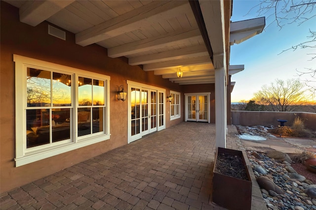 patio terrace at dusk featuring visible vents and french doors