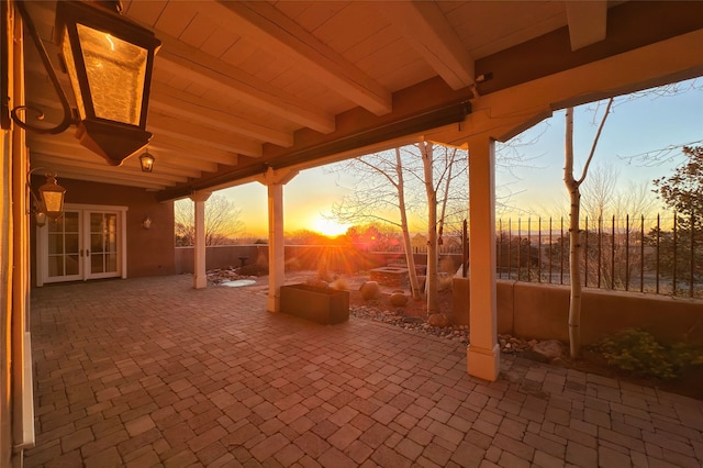 patio terrace at dusk featuring french doors and fence