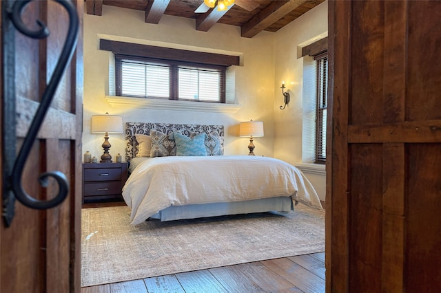 bedroom featuring a ceiling fan, beamed ceiling, wood ceiling, and wood-type flooring