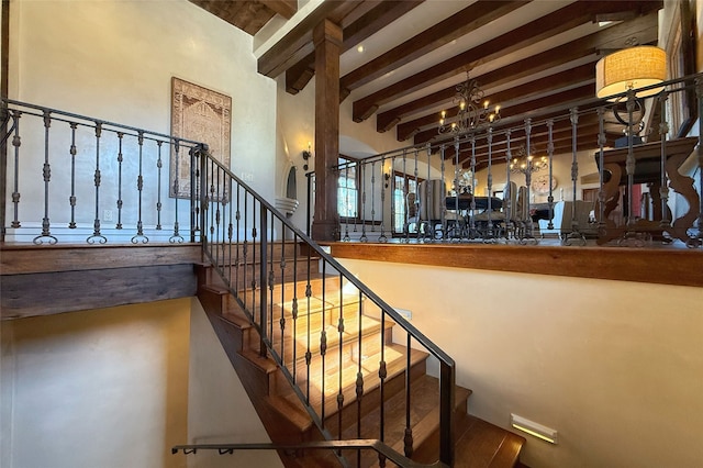 stairs with a chandelier and beamed ceiling