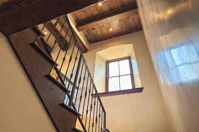 staircase featuring beam ceiling and wooden ceiling