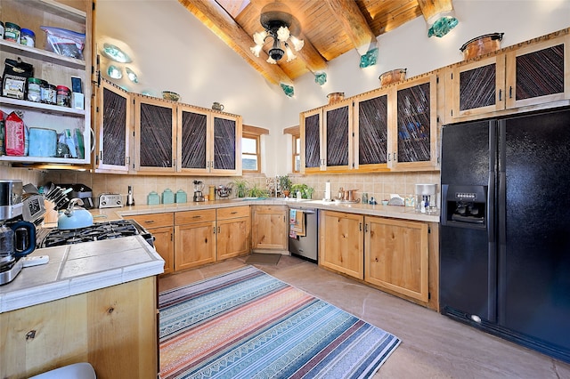 kitchen featuring backsplash, tile countertops, range with gas stovetop, black refrigerator with ice dispenser, and stainless steel dishwasher