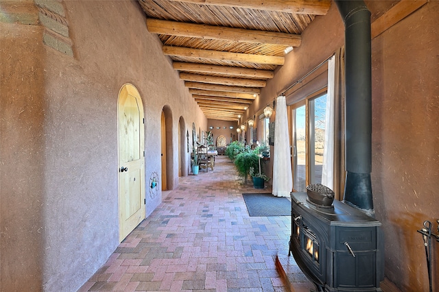 hallway with arched walkways, beamed ceiling, wooden ceiling, and brick floor