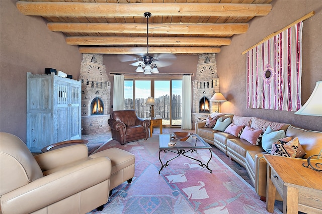 living area featuring beam ceiling, a fireplace, and ceiling fan