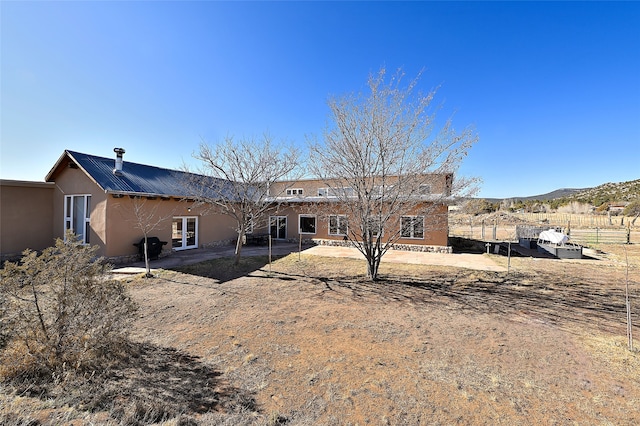 rear view of property with stucco siding, a patio, and fence