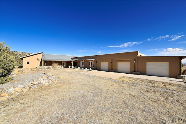 view of front facade with a garage, driveway, and stucco siding