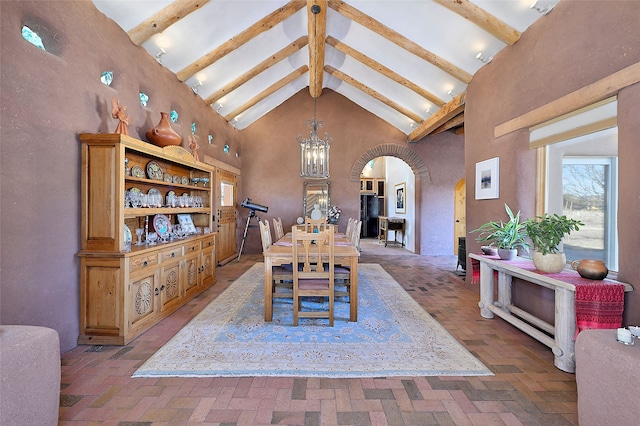 dining room with high vaulted ceiling, beam ceiling, brick floor, arched walkways, and a chandelier