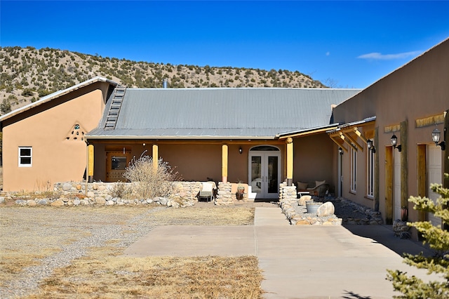 view of front of house featuring a patio, metal roof, french doors, and stucco siding