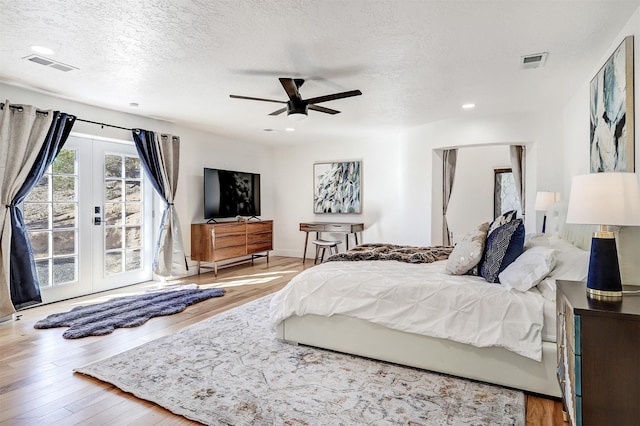 bedroom with access to outside, wood finished floors, visible vents, and french doors