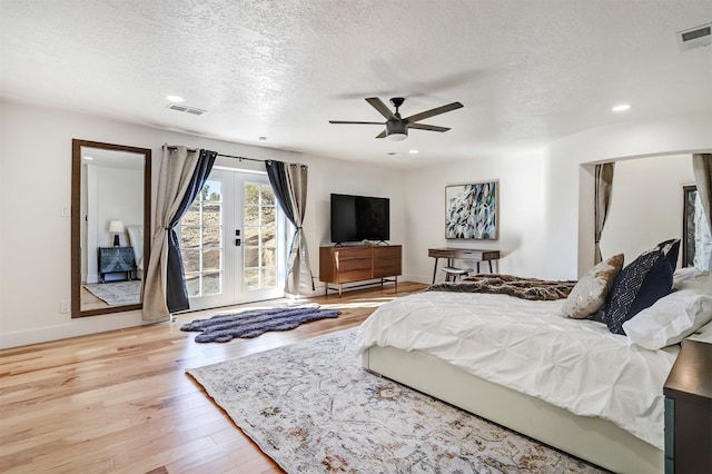 bedroom featuring wood finished floors, visible vents, french doors, a textured ceiling, and access to outside