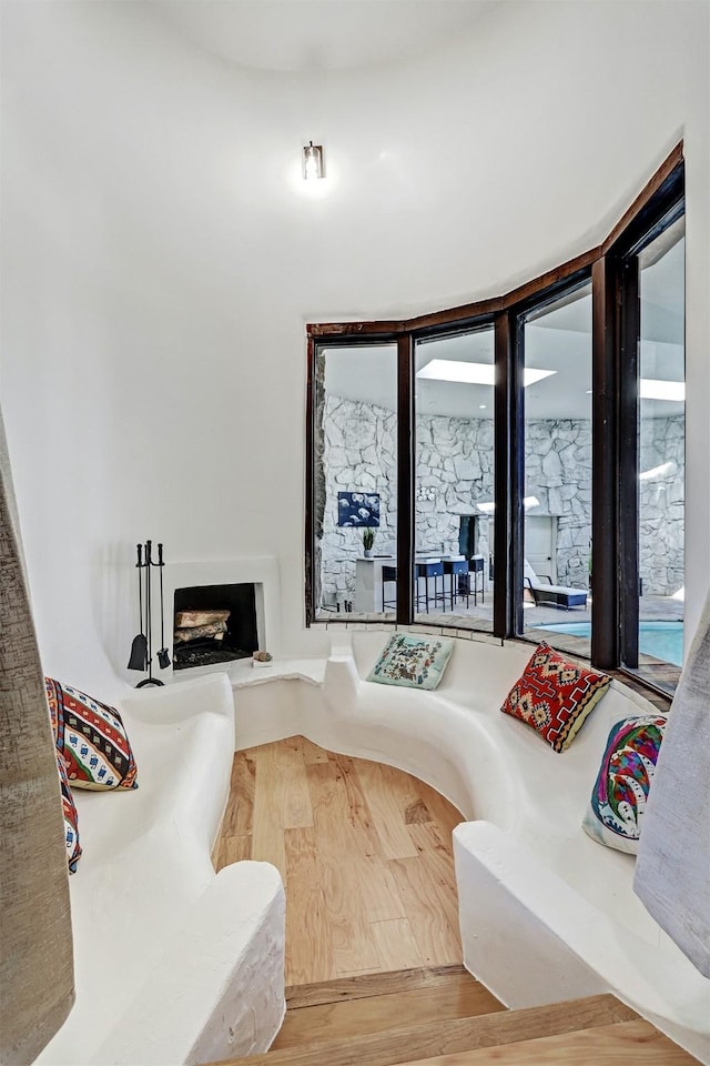 sunken living room with wood finished floors and a fireplace with raised hearth