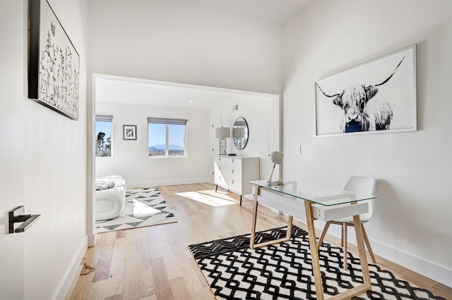 office space featuring baseboards, a high ceiling, and wood finished floors