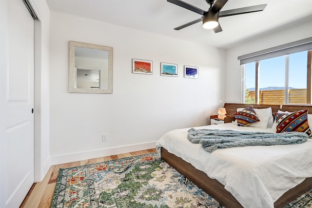 bedroom with baseboards, wood finished floors, and a ceiling fan