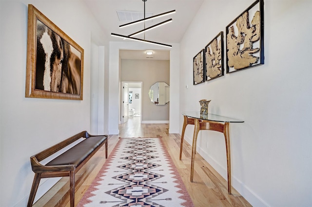 hallway featuring visible vents, light wood-type flooring, and baseboards